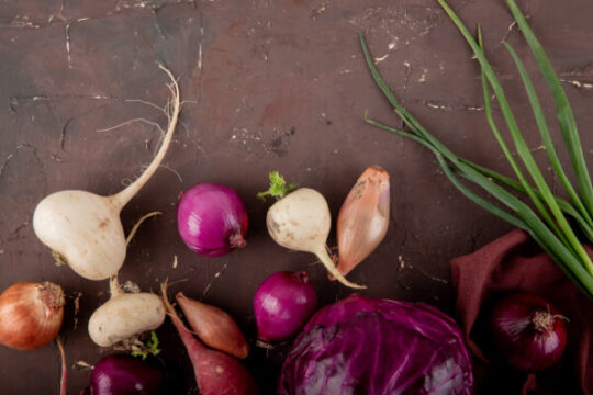 close up view vegetables as radish onion purple cabbage onion maroon background with copy space