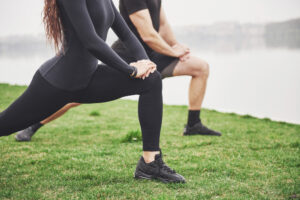 fitness couple stretching outdoors park near water young bearded man woman exercising together morning