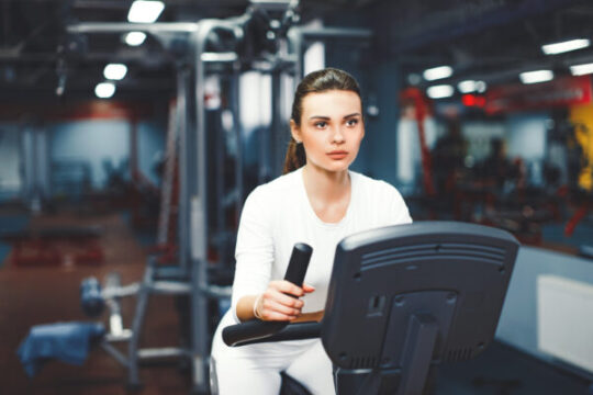 Elliptical Routine indoor cycling woman doing cardio workout biking indoors gym bike 1