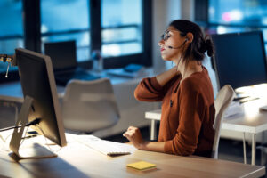 shot tired business woman with back pain looking uncomfortable while working with computers office