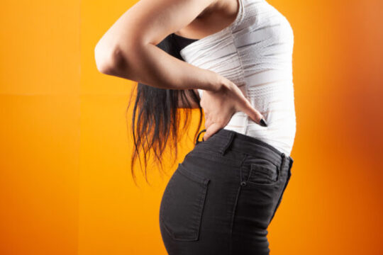 young woman has kidney pain orange background