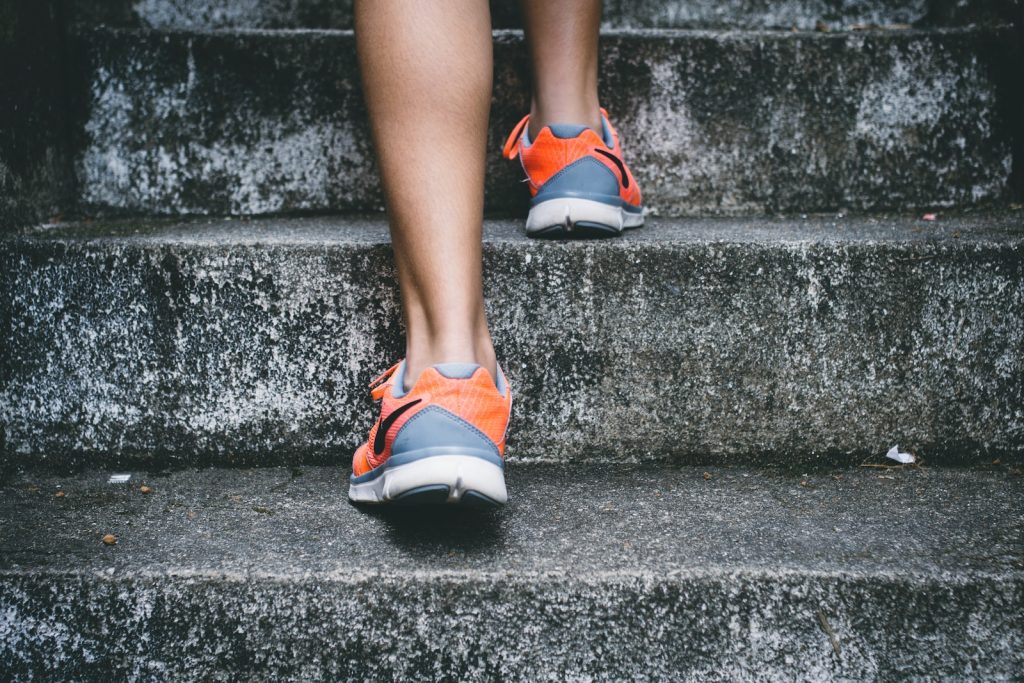 work out person wearing orange and gray Nike shoes walking on gray concrete stairs