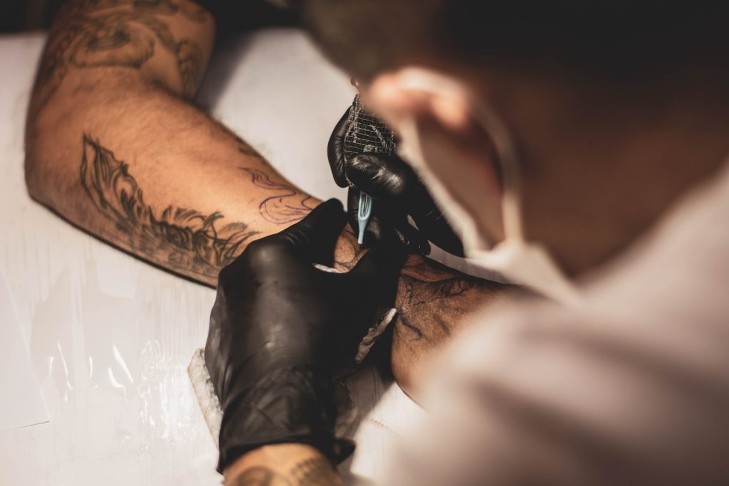 shallow focus photo of person tattooing person's right arm Exploring the Motivation Behind Gym Logo Tattoos: Unveiling the Fascination