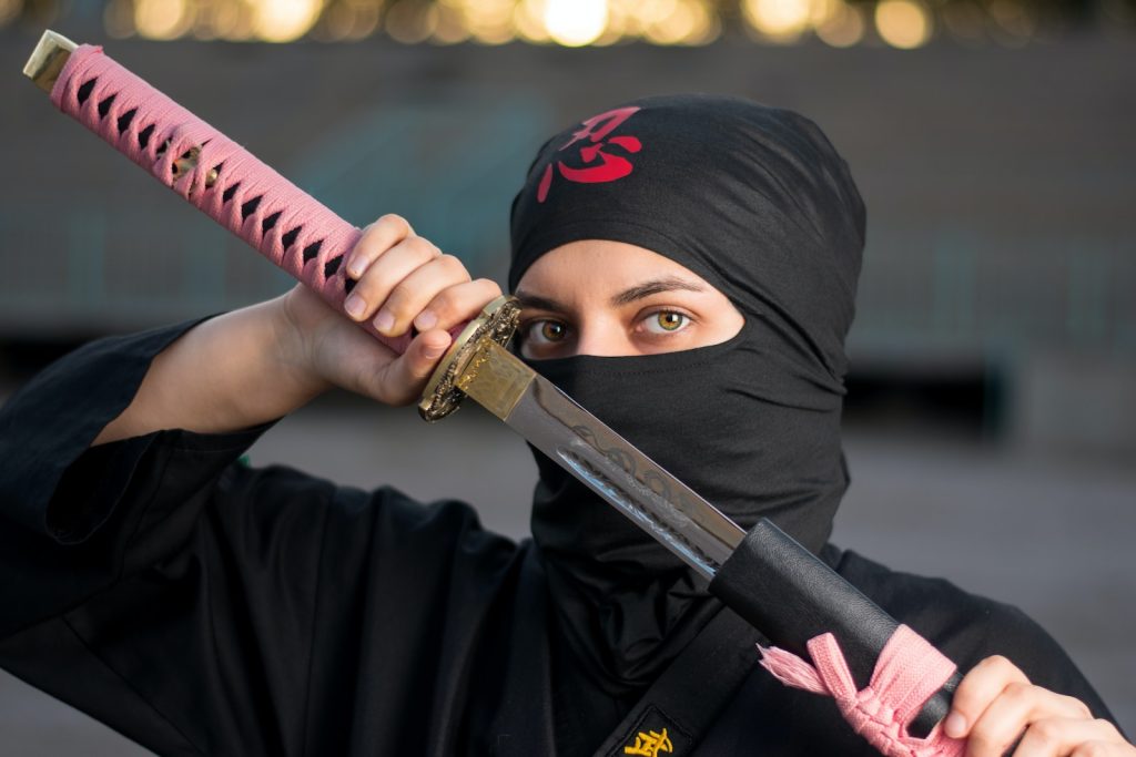 Ninja Turtle woman in black hijab holding pink and black sword