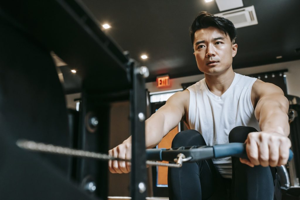 Focused ethnic sportsman doing exercises on rowing machine 21-Day Training Plan for Mastering the Rowing Machine