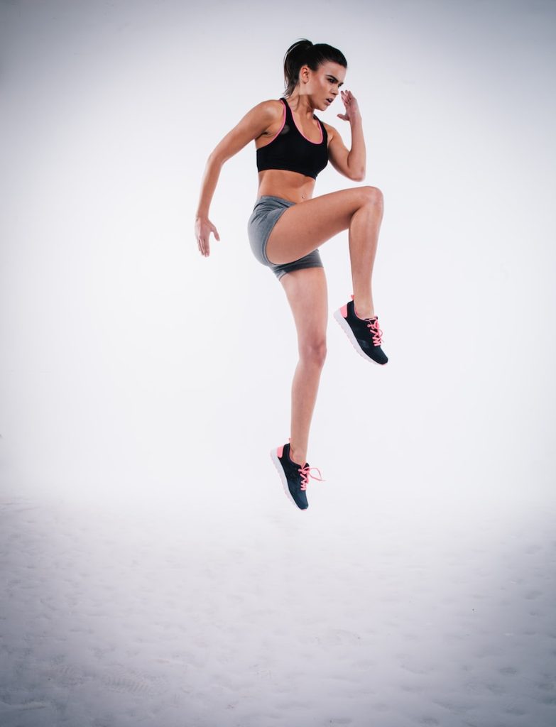 Conditioning Workout woman jumping near white wall paint